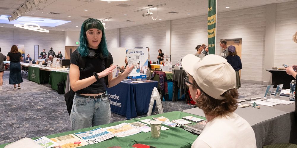 A student talks with a vendor tabling at the democracy summit resource fair