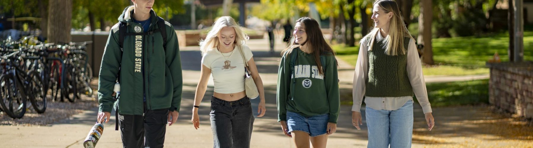 Four students wearing CSU clothing walk across campus