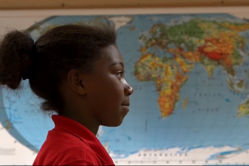 Student standing in front of a world map