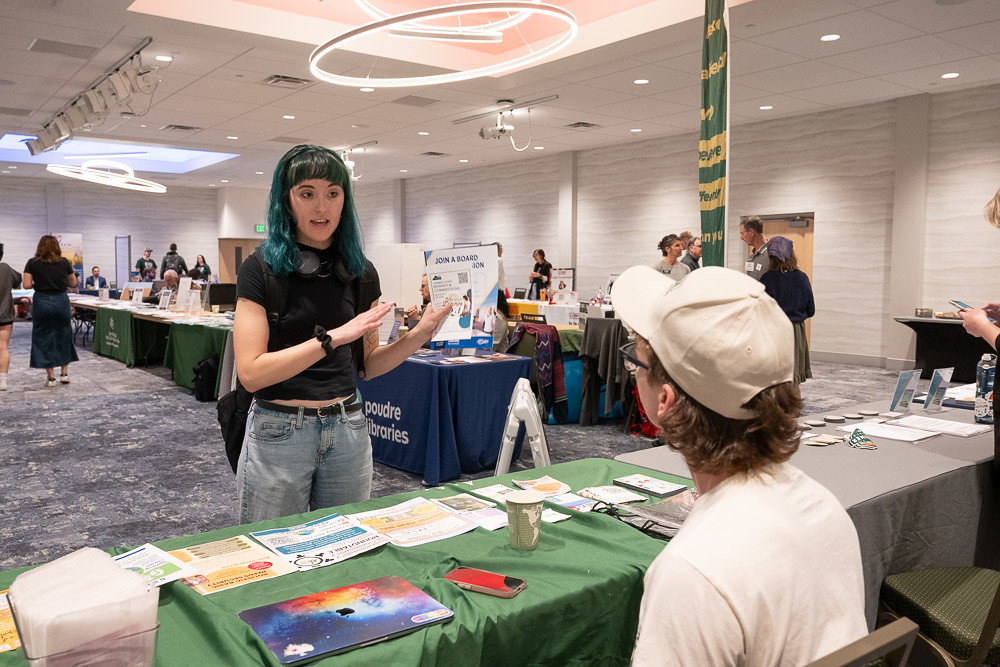 A student talks with a vendor tabling at the democracy summit resource fair